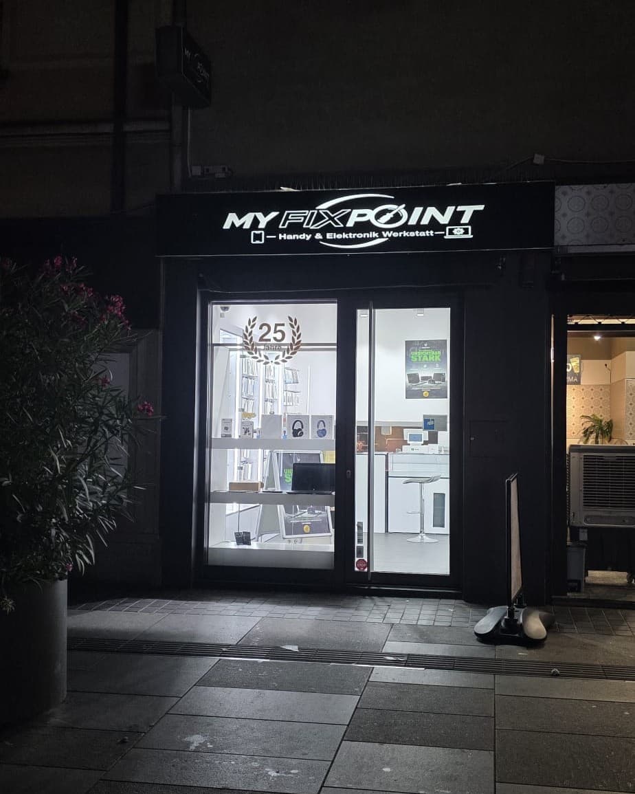 Die beleuchtete Ladenfront von MY FIX POINT bei Nacht, das Schaufenster zeigt die hellen Verkaufsräume.
