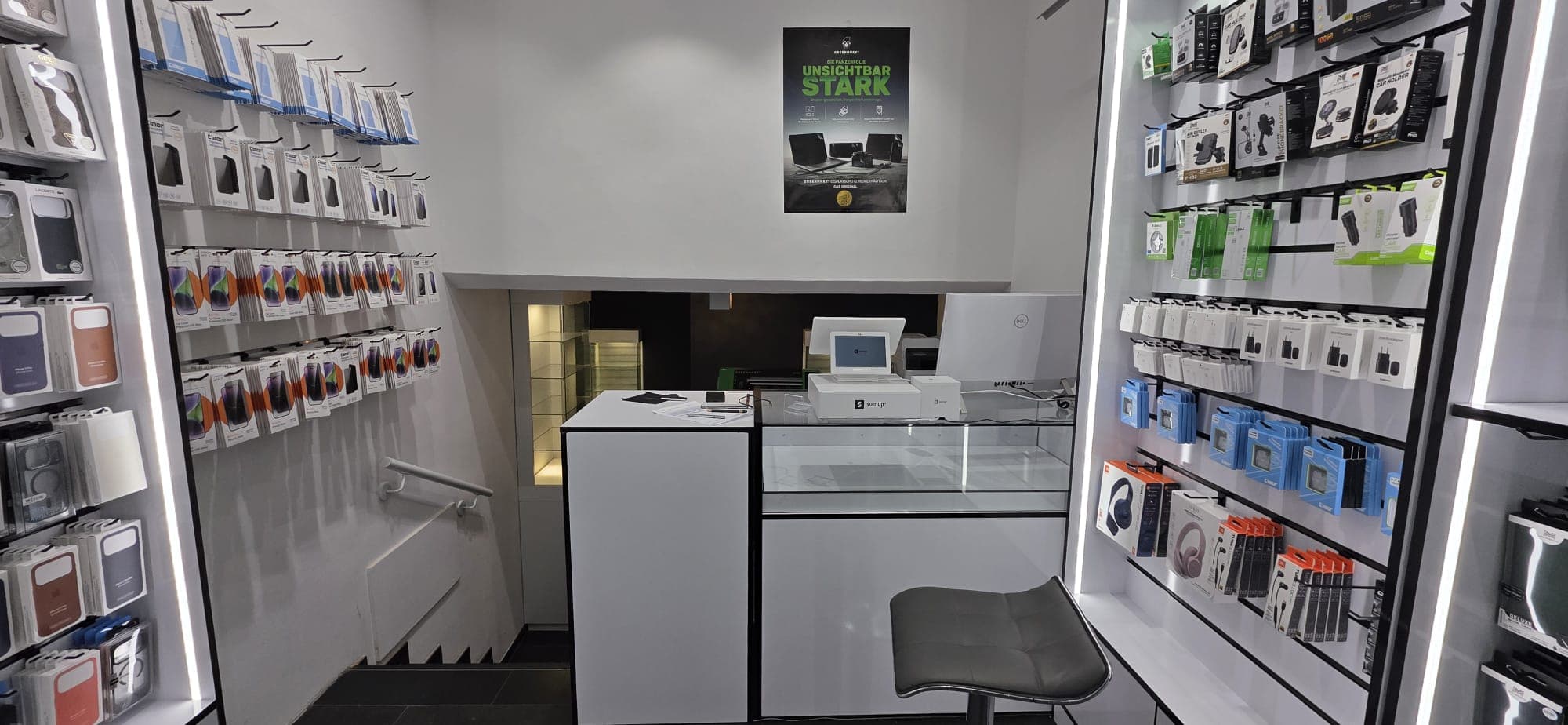 Der Tresen von MY FIX POINT mit Kasse und Glasvitrine, umgeben von Regalen mit Displayschutz, Ladegeräten und Kopfhörern.